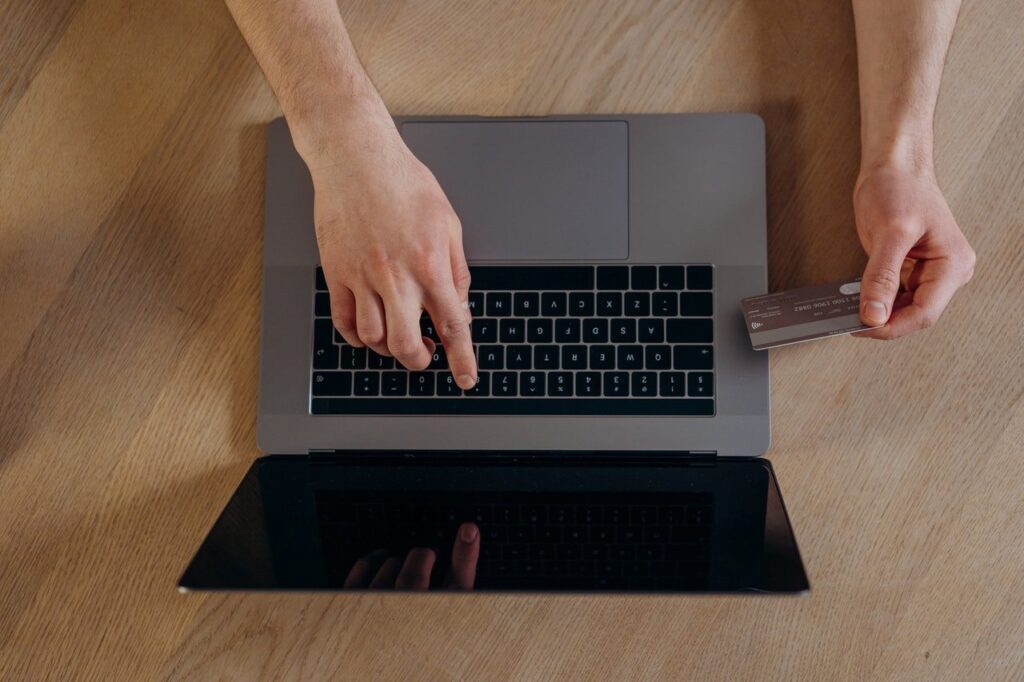 Pessoa mexendo em notebook, segurando um cartão de crédito Bankinter Premier