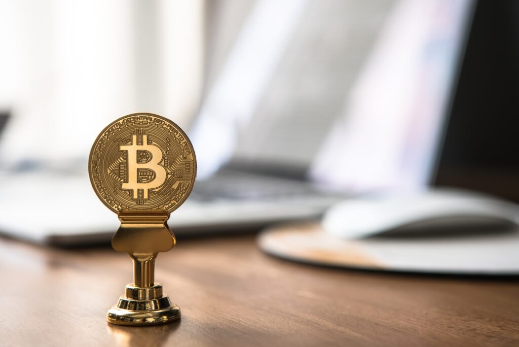 criptomoeda Bitcoin suspensa em haste com computador ao fundo