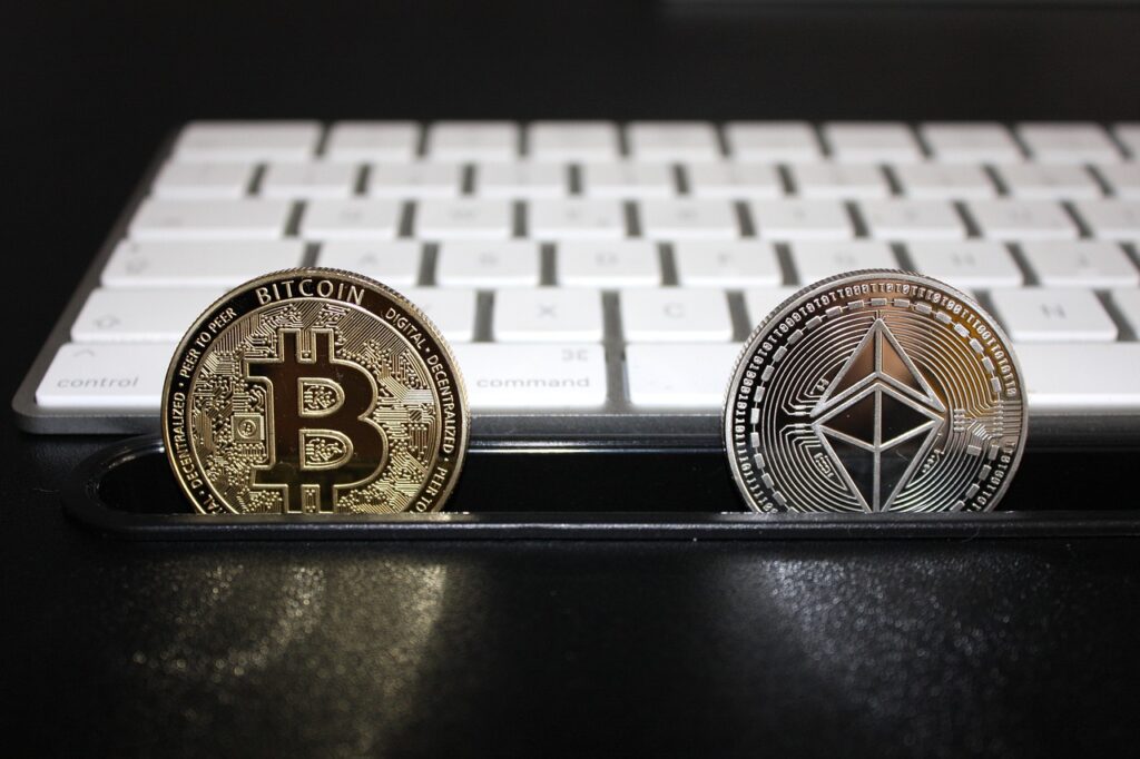 Criptomoedas Bitcoin e Ethereum em frete à teclado de computador. Ambas disponíveis na corretora Cripto.com