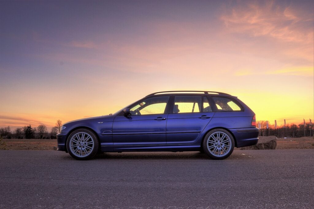 Carro azul estacionado, pôr do sol ao fundo.