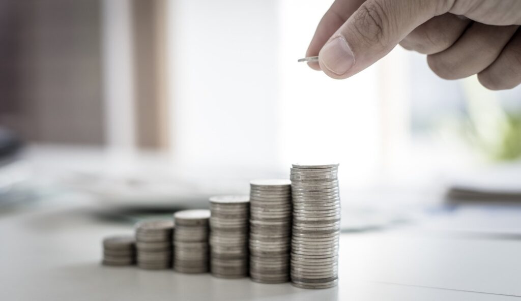 Pessoa empilhando moedas, em pilhas crescentes. Representando o lucro possível com a Corretora AvaTrade