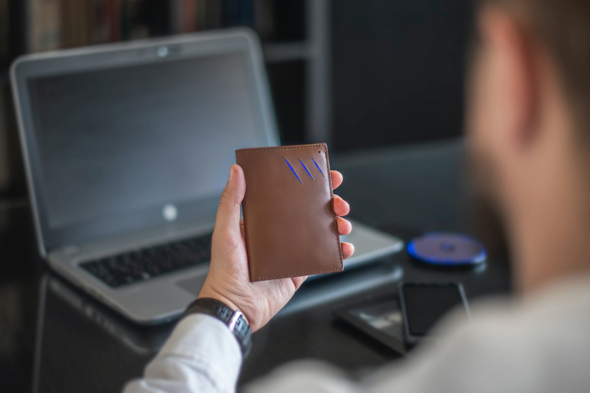 Homem segurando carteira, em frente a um notebook. Simbolizando como fazer crédito de alto valor