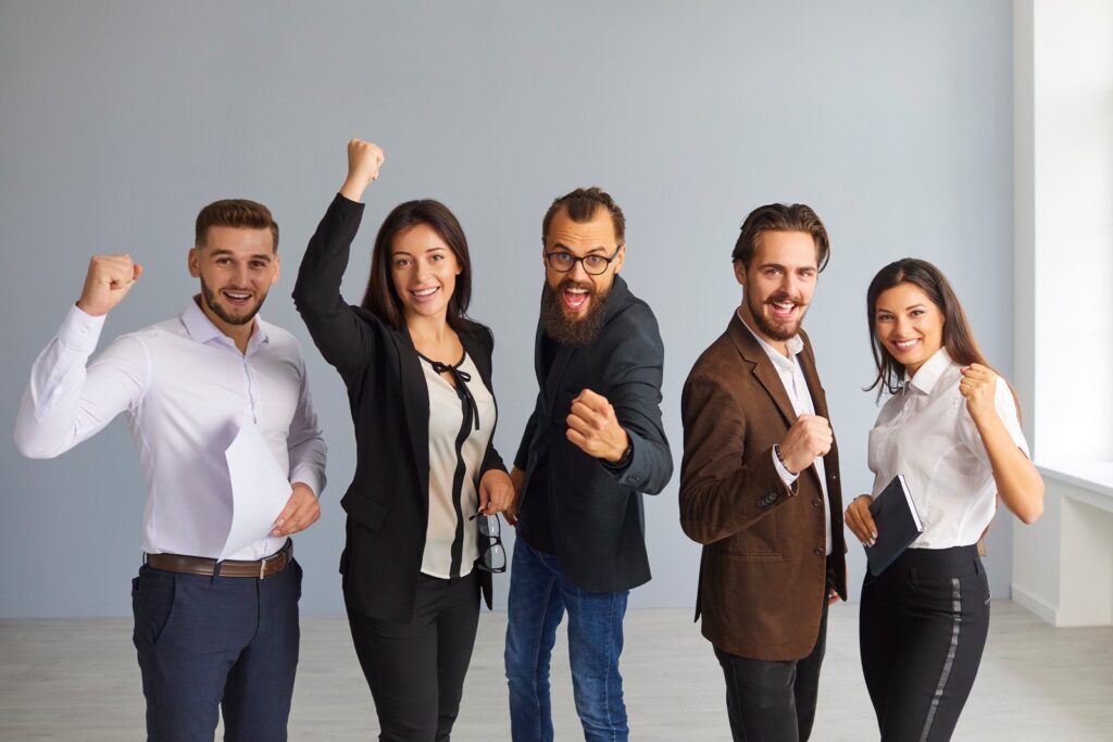 Grupos de cinco jovens, de roupa social, animados e fazendo gestos de comemoração. Simbolizando o Movimento Júnior português