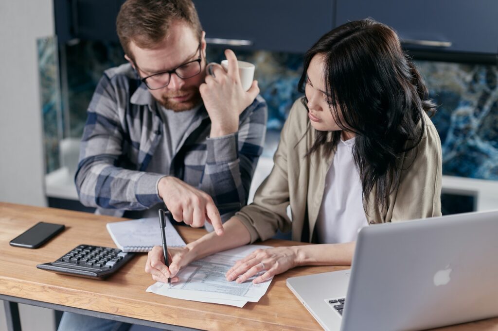 homem e mulher fazendo contas para transferência de crédito habitação em frente a notebook