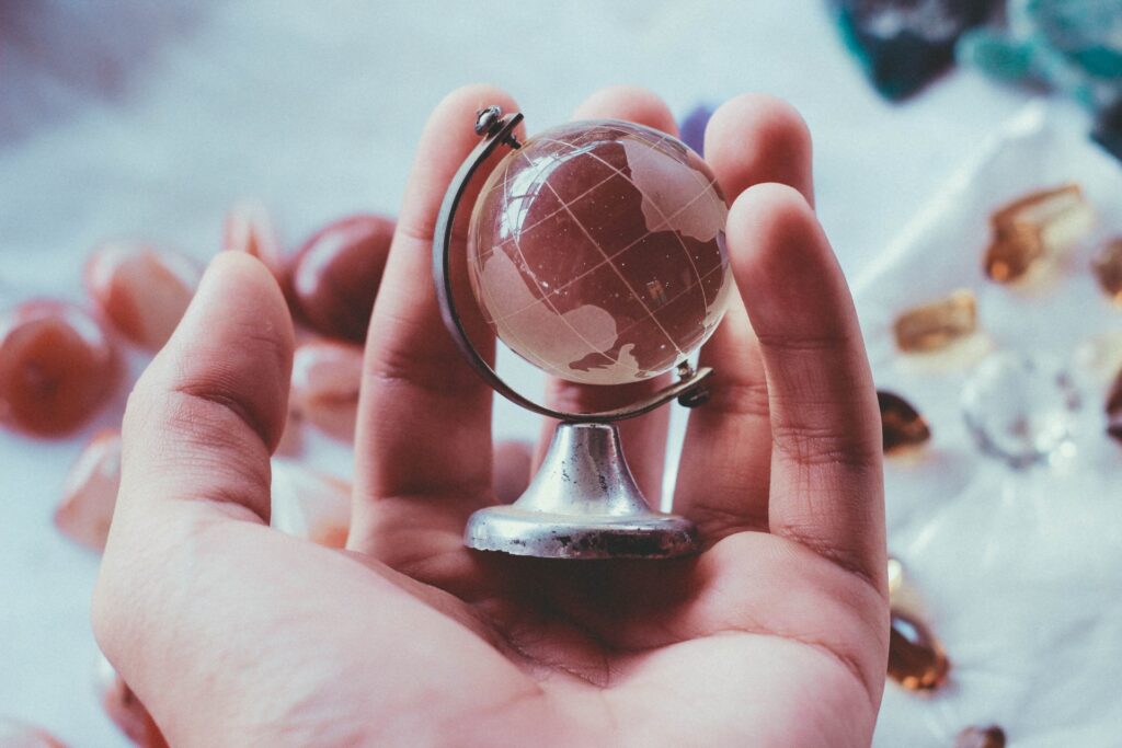 Mão segurando um globo terrestre de cristal e metal, simbolizando os enefícios cartões de crédito TAP