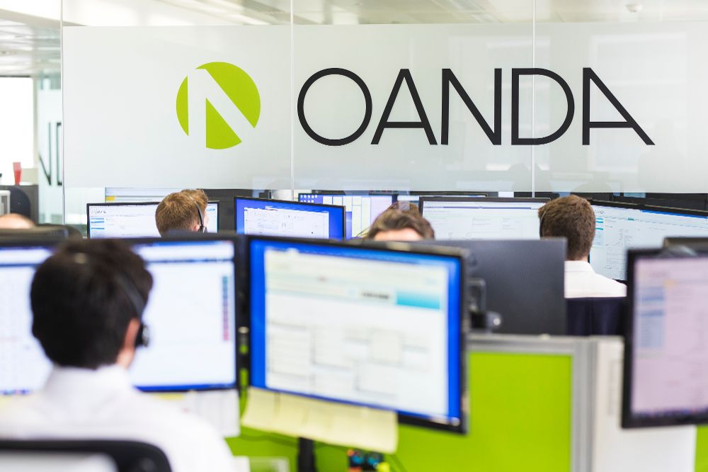 pessoas trabalhando em computador em escritório da corretora Oanda