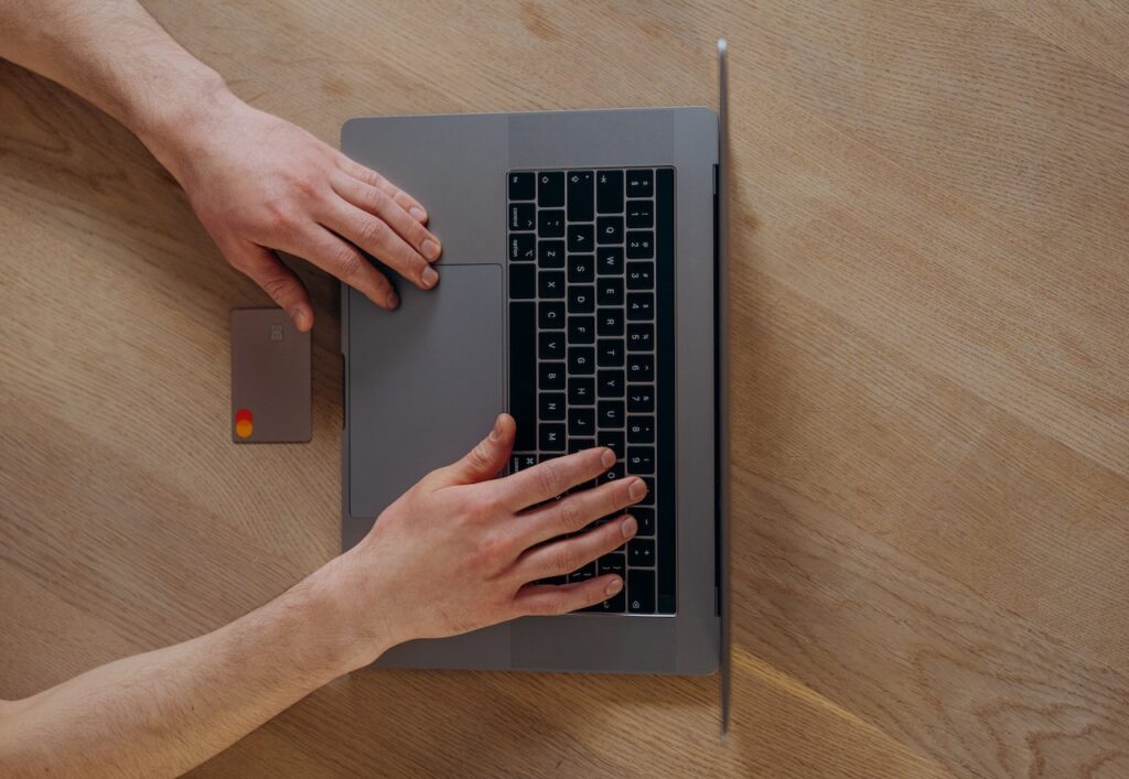pessoa digitando em notebook com cartão de crédito ao lado