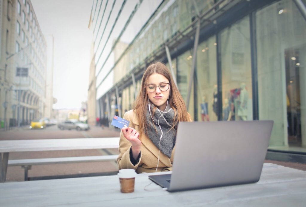 mulher mexendo no computador com um cartão de crédito na mão