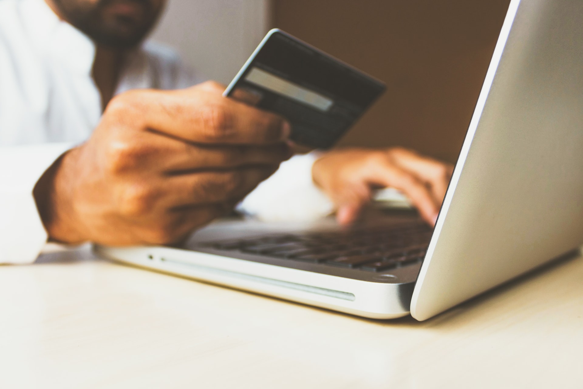 pessoa segurando um cartão de crédito na mão enquanto mexe no computador