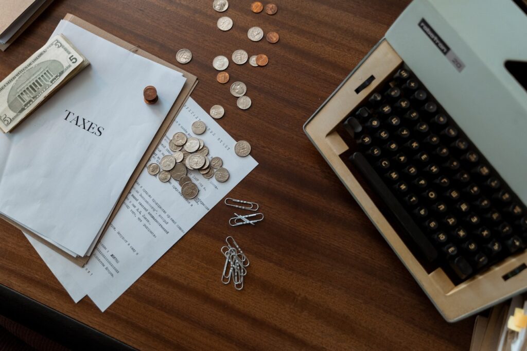 imagem com vários papéis sobre a mesa com moedas e um notebook para a pesquisa