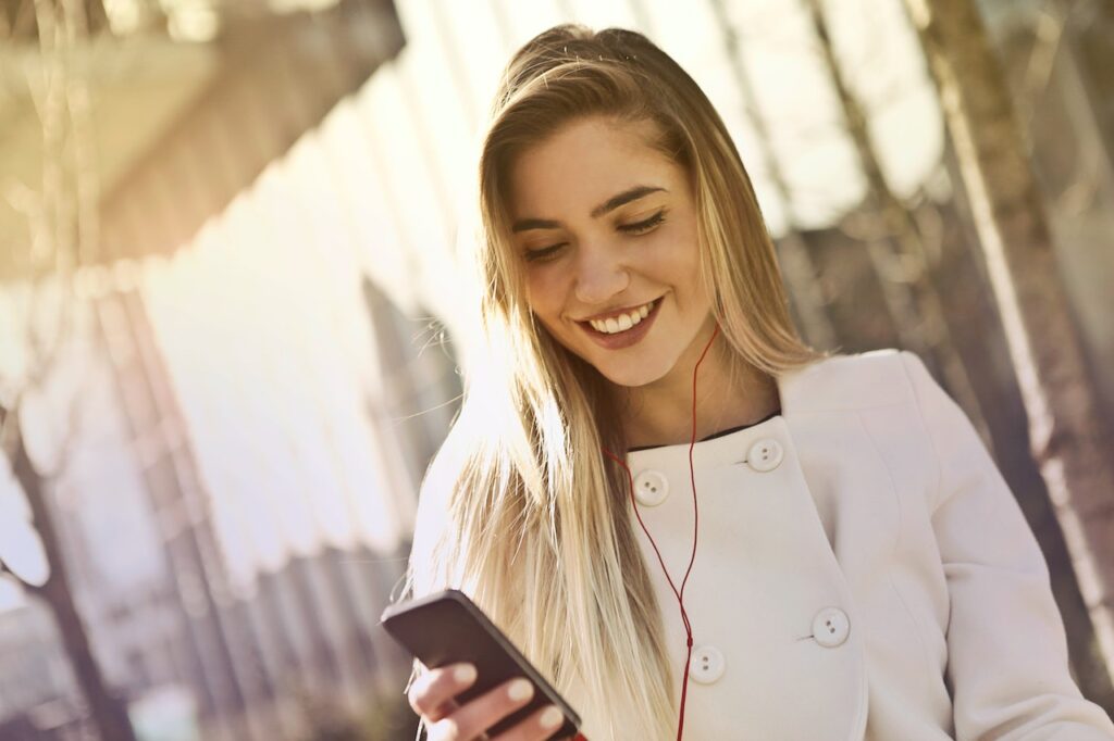 mulher com o celular na mão e fones de ouvido