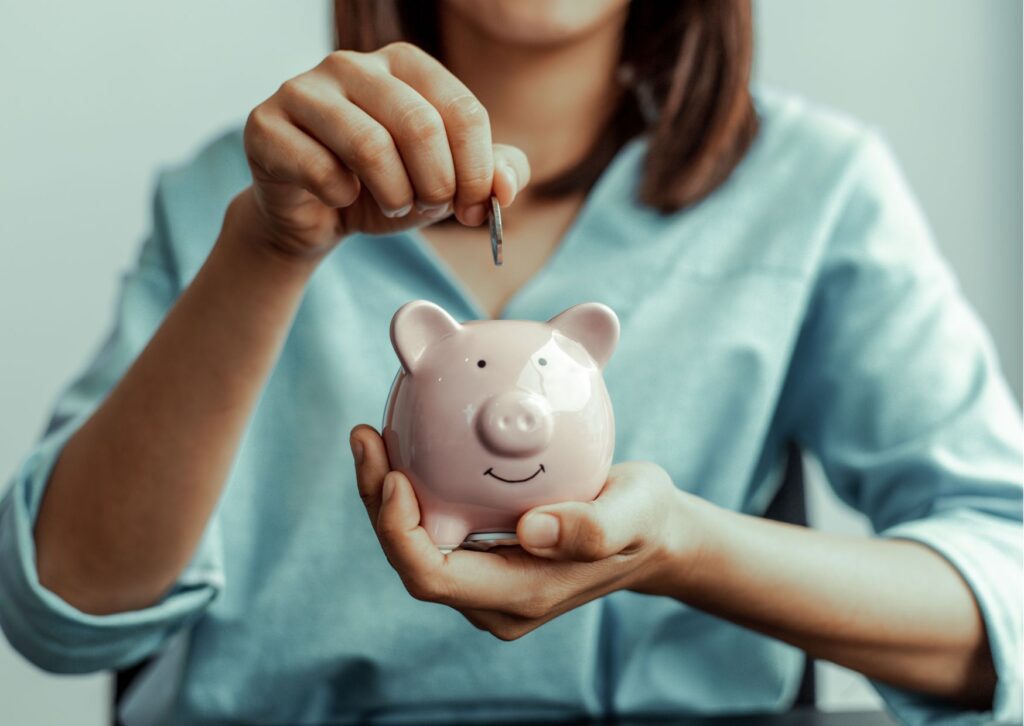 pessoa colocando moedas em um porquinho rosa