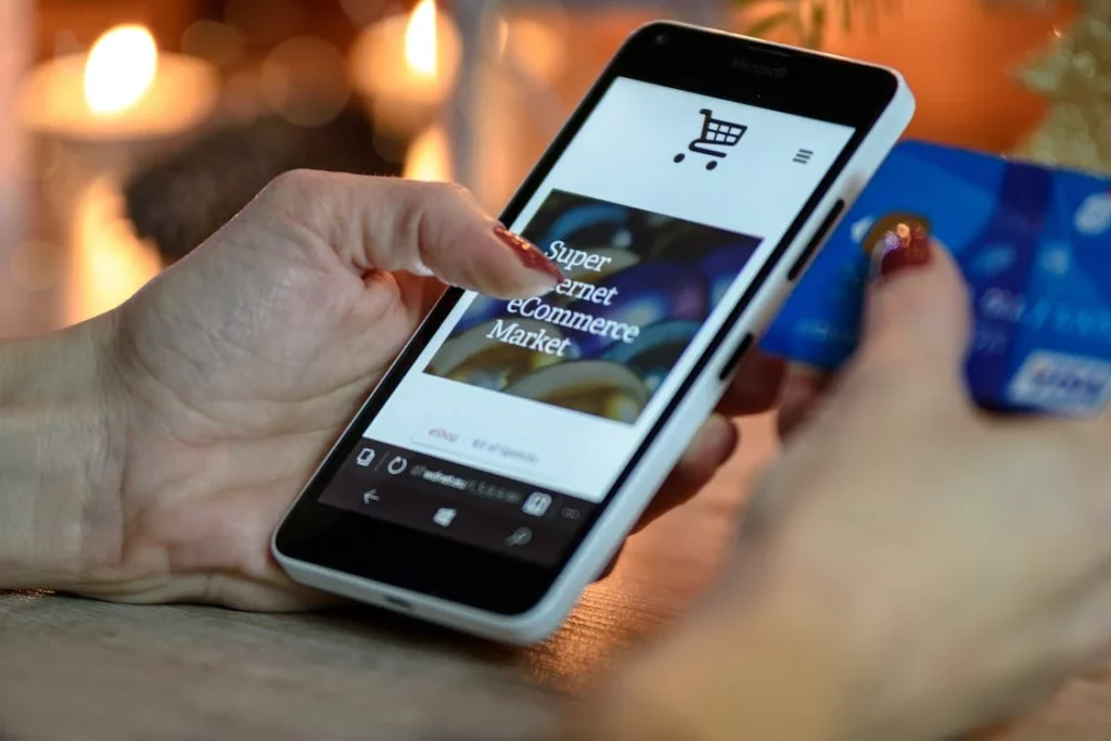 Mão usando celular para fazer compras