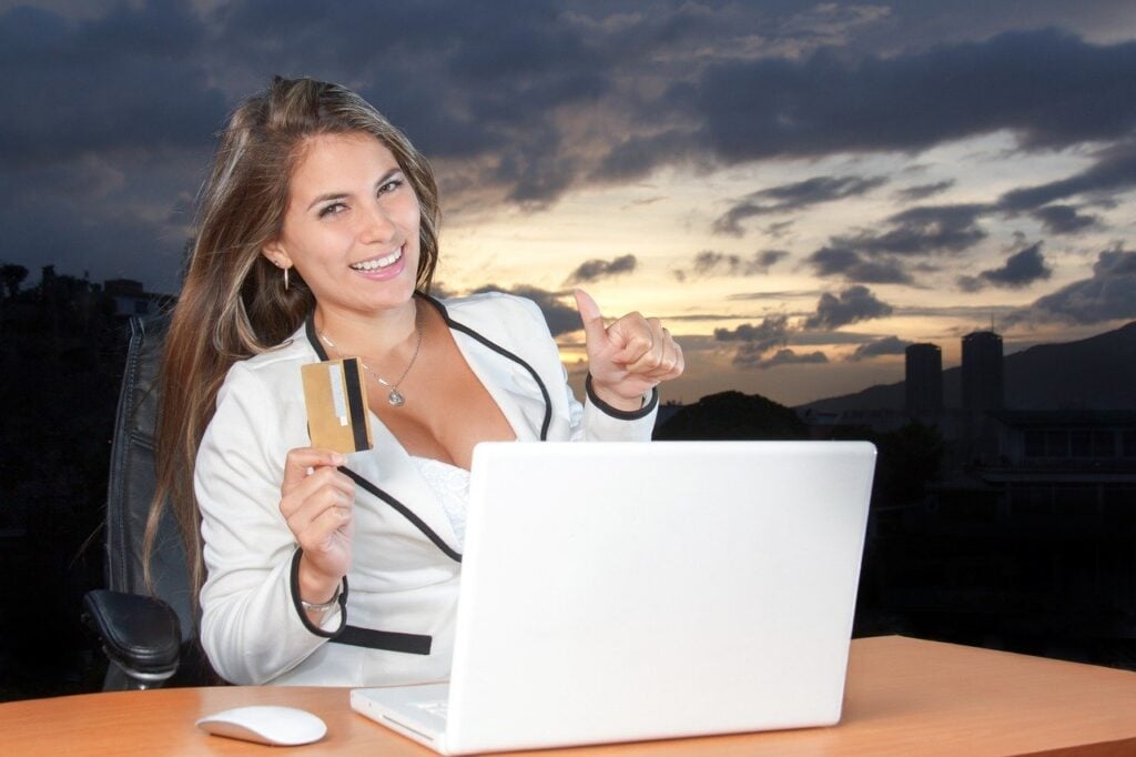 Mulher festejando com cartão de crédito e notebook