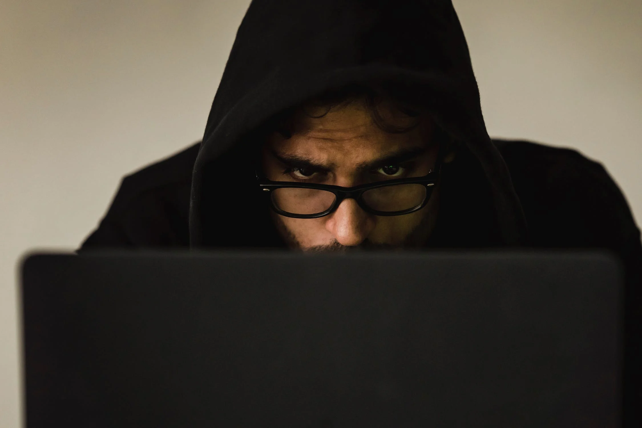 Homem sério olhando por cima da tela do notebook