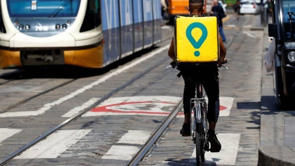 Pessoa de bicicleta e mochila de entrega com logo Glovo