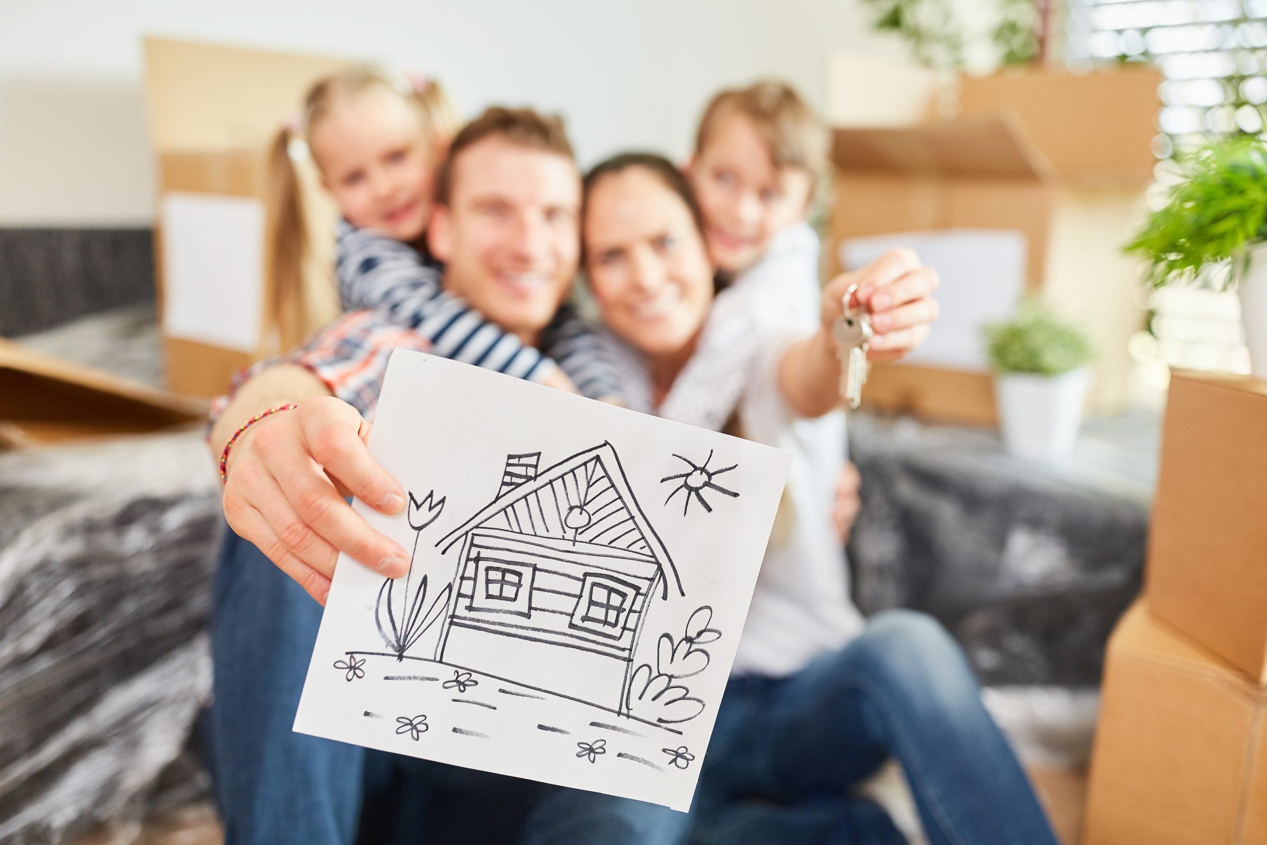 Família feliz segurando chave de casa e desenho de casa