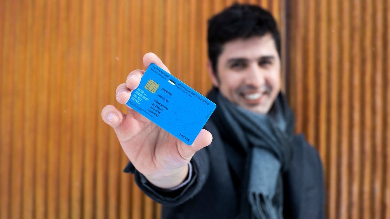 Homem sorrindo segurando cartão e-Residency