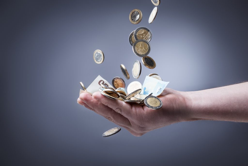 Mão amparando notas e moedas de euro