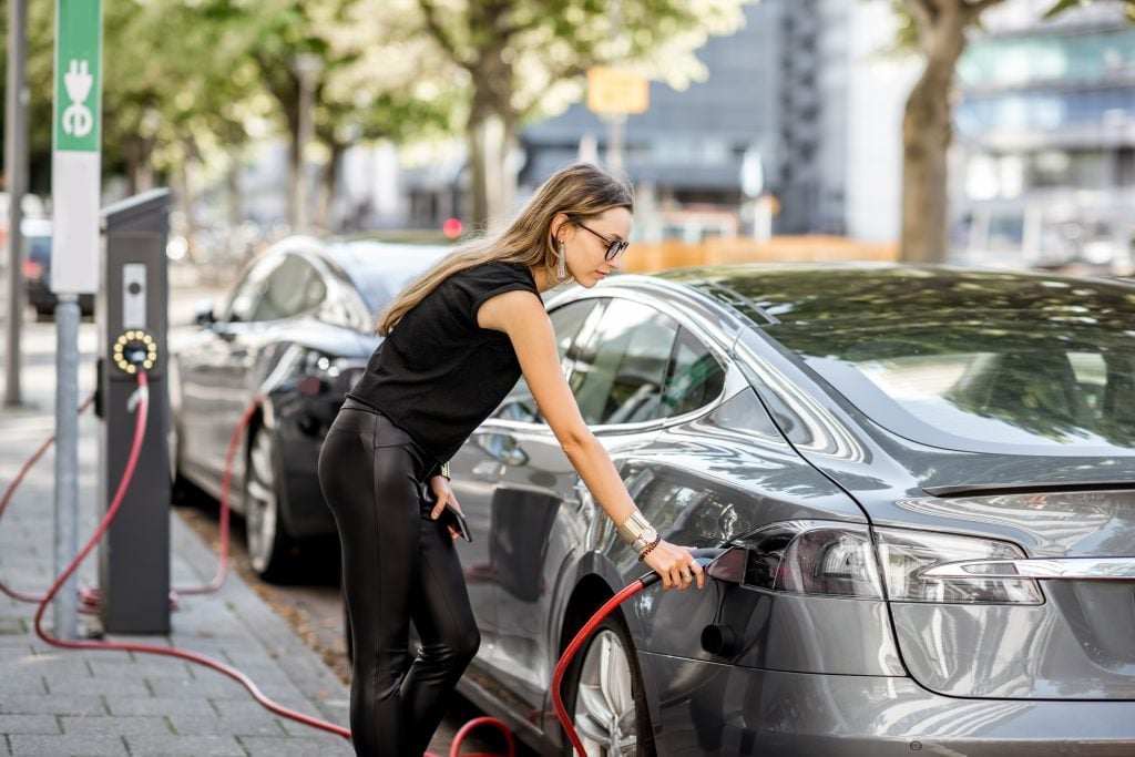 Mulher carregando carro elétrico