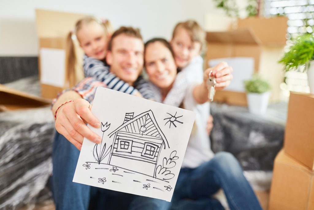 Família feliz segurando chave de casa e desenho de casa