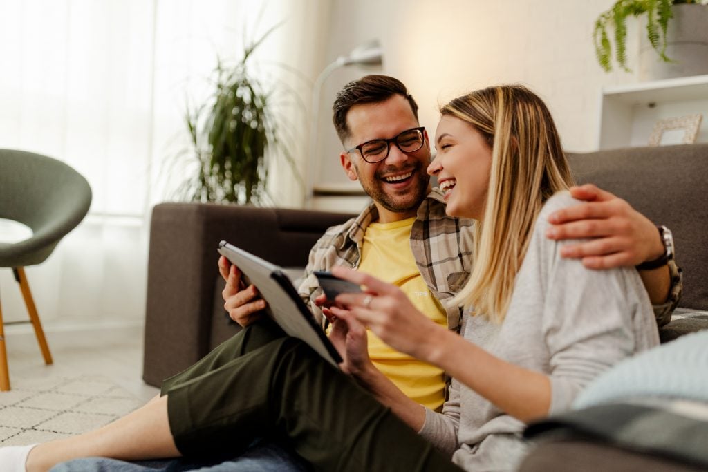 Couple shopping online. Happy couple looking together sitting floor at home.