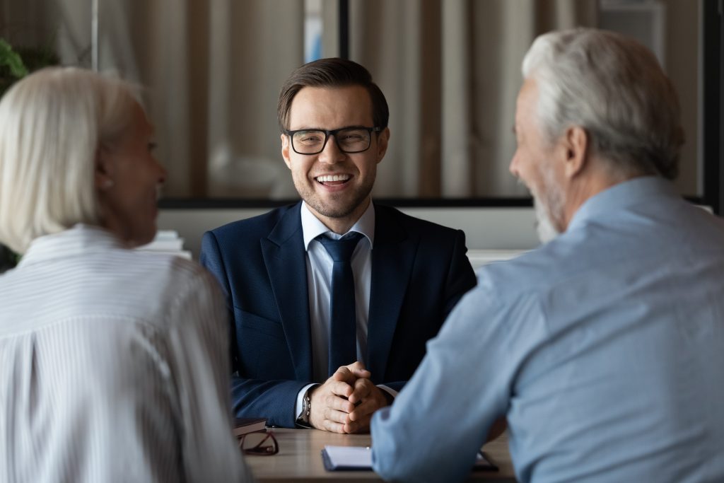 Homem de negócios sorrindo e conversando com casal de idosos
