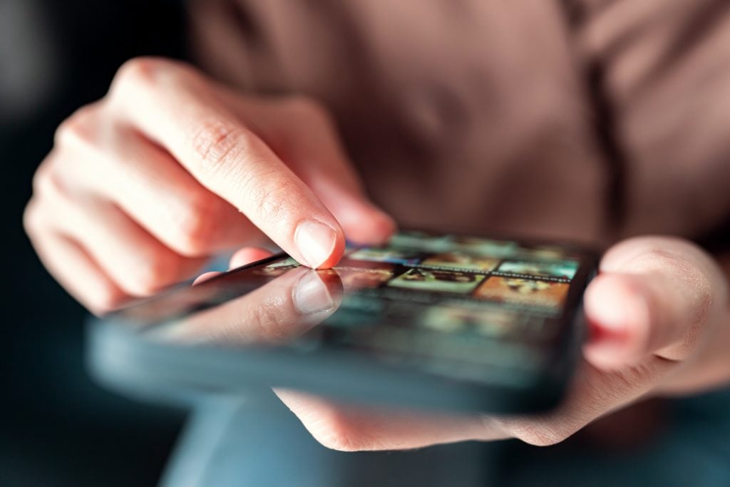 Online movie stream with mobile phone. hand of woman choosing fi
