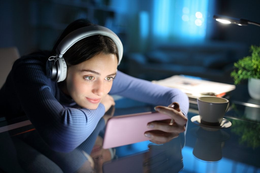 Woman watching media on smart phone in the night at home