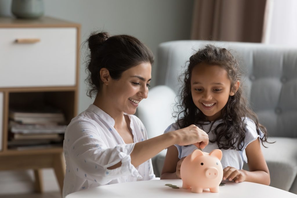 Mãe e filha guardando dinheiro em porquinho