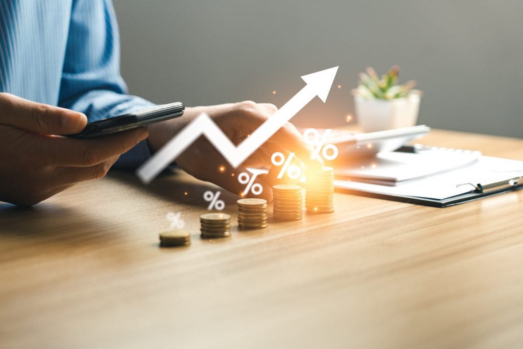 Pilhas crescentes de moedas com seta de gráfico subindo sobre elas