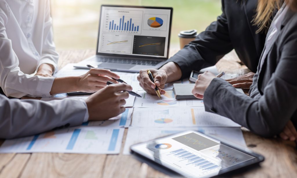 Pessoas em reunião de finanças com gráficos na tela no notebook