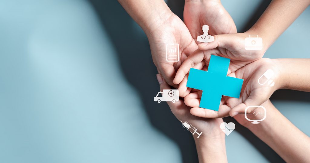 Mãos de adultos e crianças juntas segurando o símbolo da saúde