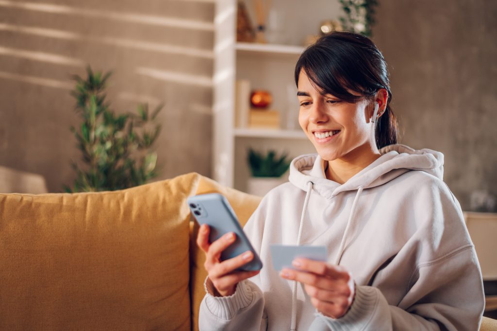 Woman using smartphone and holding credit card while online shop