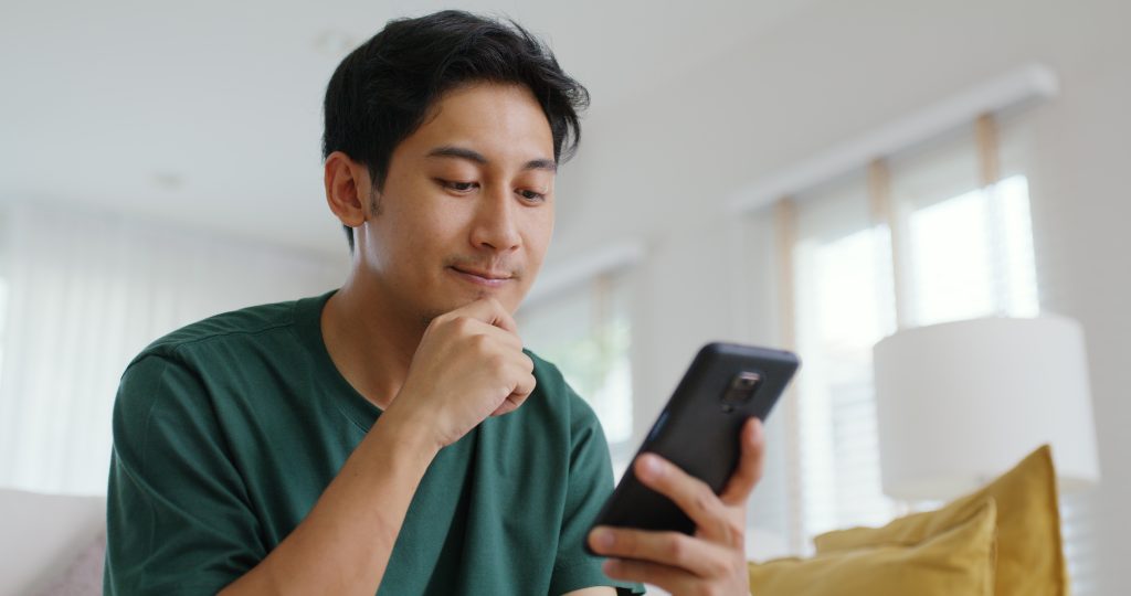 Homem pensativo olhando celular
