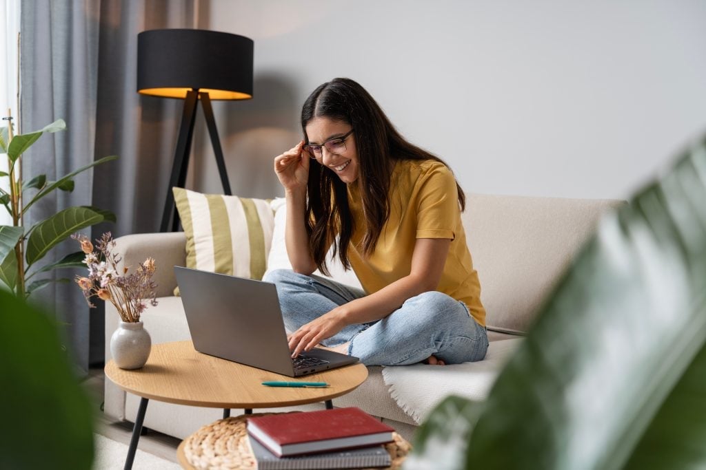 Back to study. Happy student doing her work at home on laptop in a cosy room